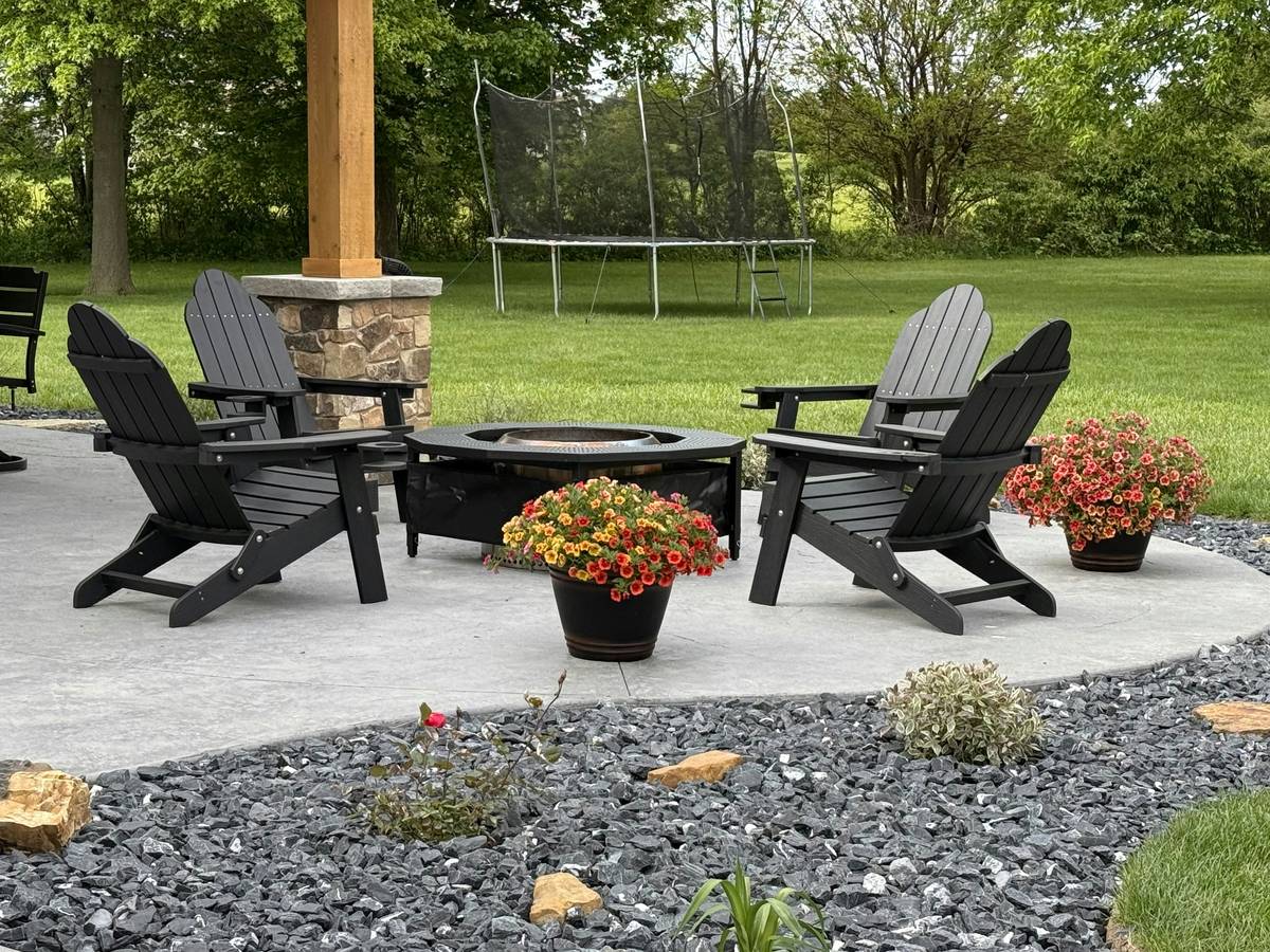 Foldable lawn furniture design shown assembled on a sloped backyard lawn with visible double-pivot hinges and reinforced cross-bracing